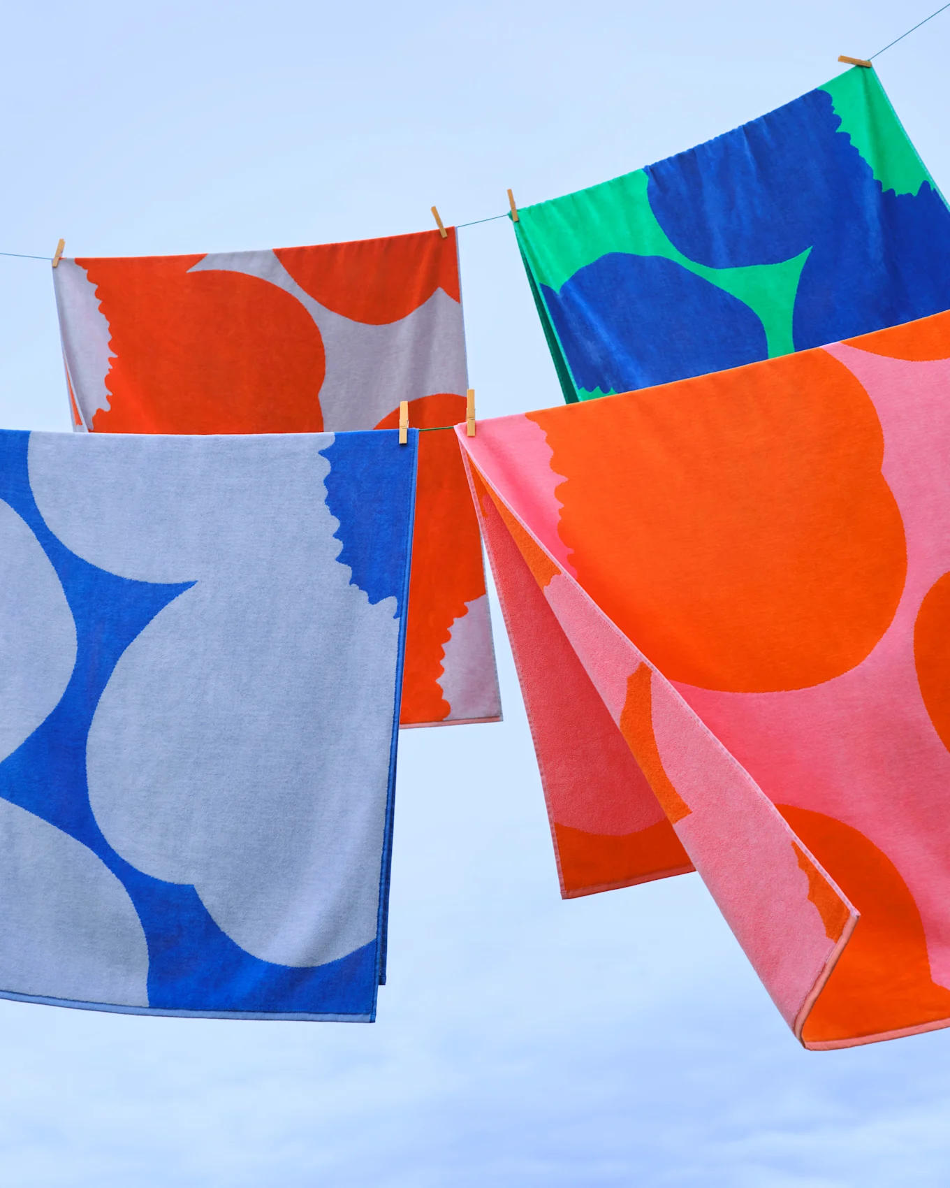 Serviettes colorées à motifs suspendues à une corde à linge sur un ciel bleu.