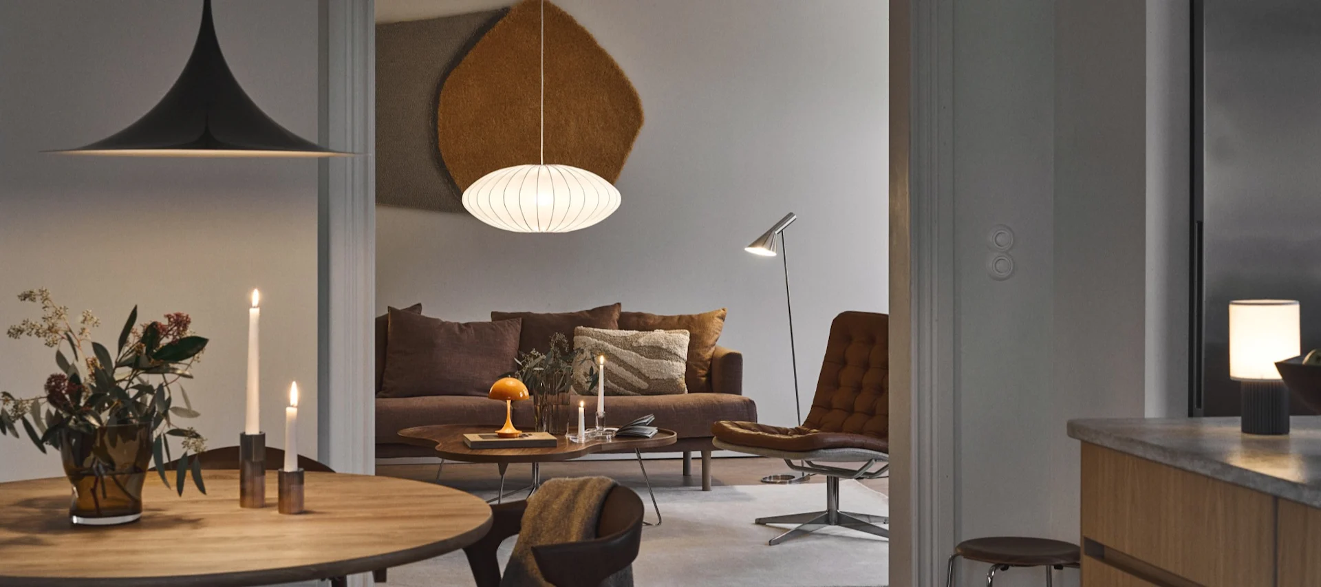 Homme lisant sur un canapé confortable dans un salon chaleureux et éclairé par des lampes, avec table basse, panier et tapis.
