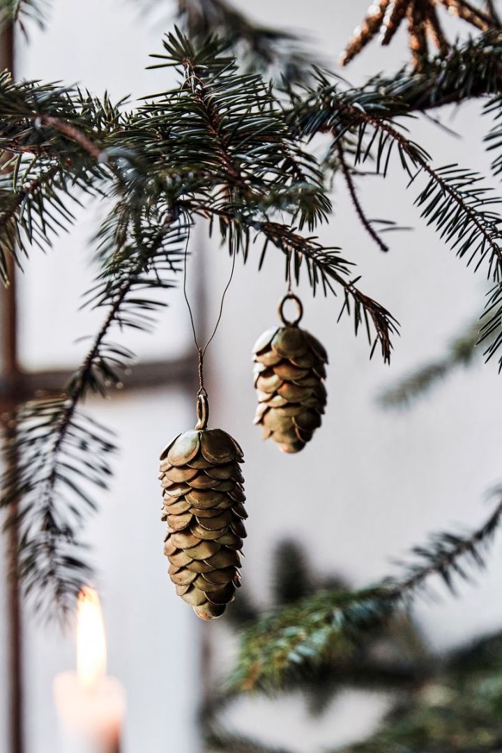 Utilisez des idées de décoration de sapin de Noël inspirées de la nature, comme les pommes de pin en laiton de House Doctor. 