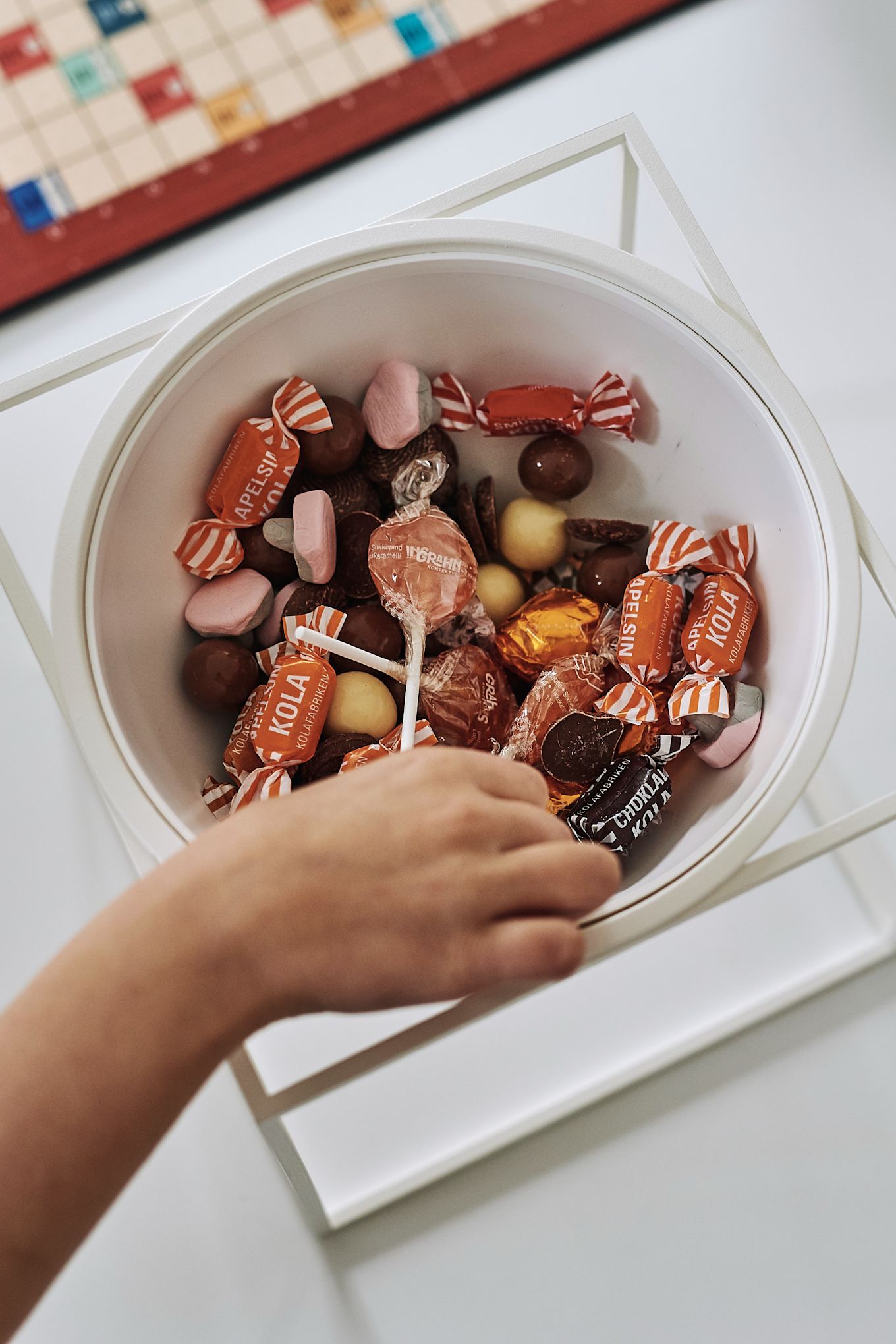 Une main choisit un bonbon dans le bol blanc Kubus d'Audo Copenhagen.