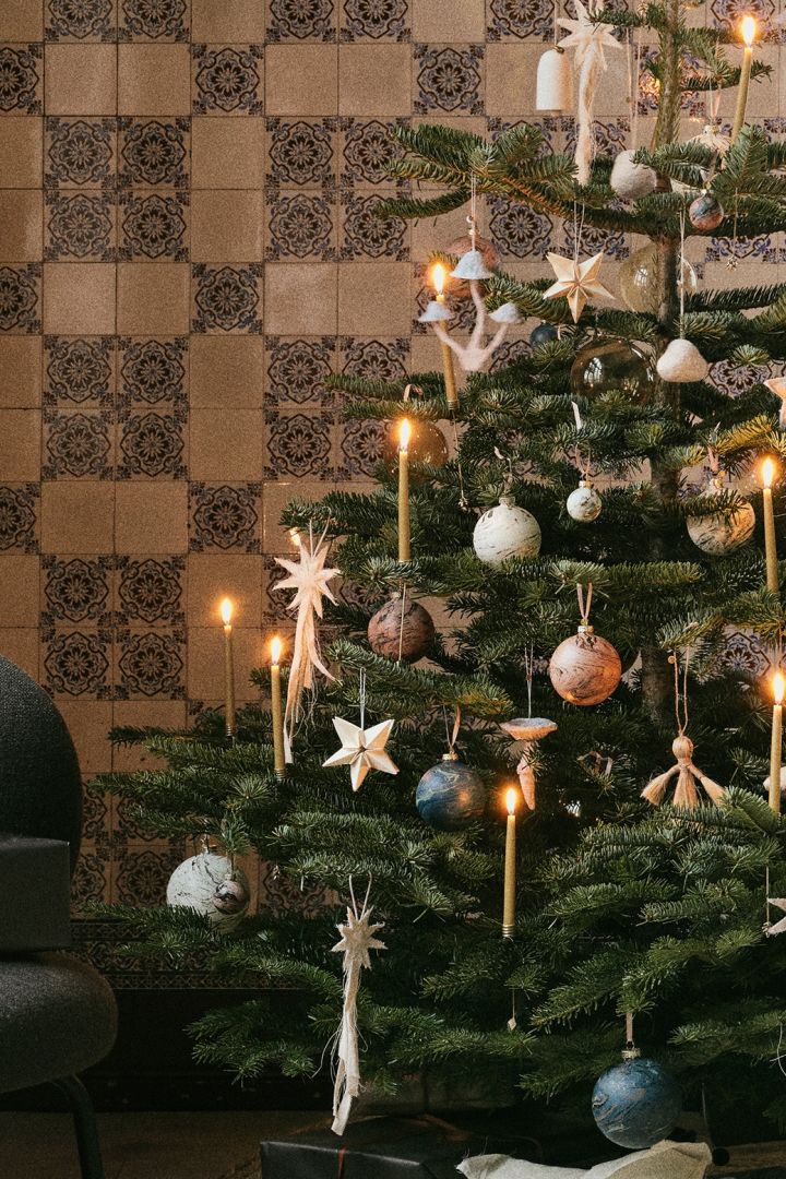 Idées de décorations naturelles pour le sapin de Noël de ferm LIVING. Voici un sapin décoré d'étoiles, de cloches et de champignons en feutre, dans la palette de couleurs de la nature.