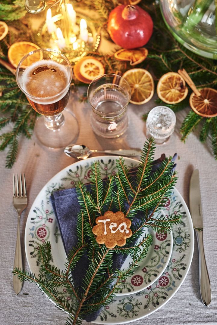 Une décoration de table de Noël digne d'un conte de fées : Utilisez la porcelaine d'hiver Swedish Grace de Rörstrand et placez-y une serviette et une branche de sapin, ainsi qu'un biscuit pour indiquer la place.