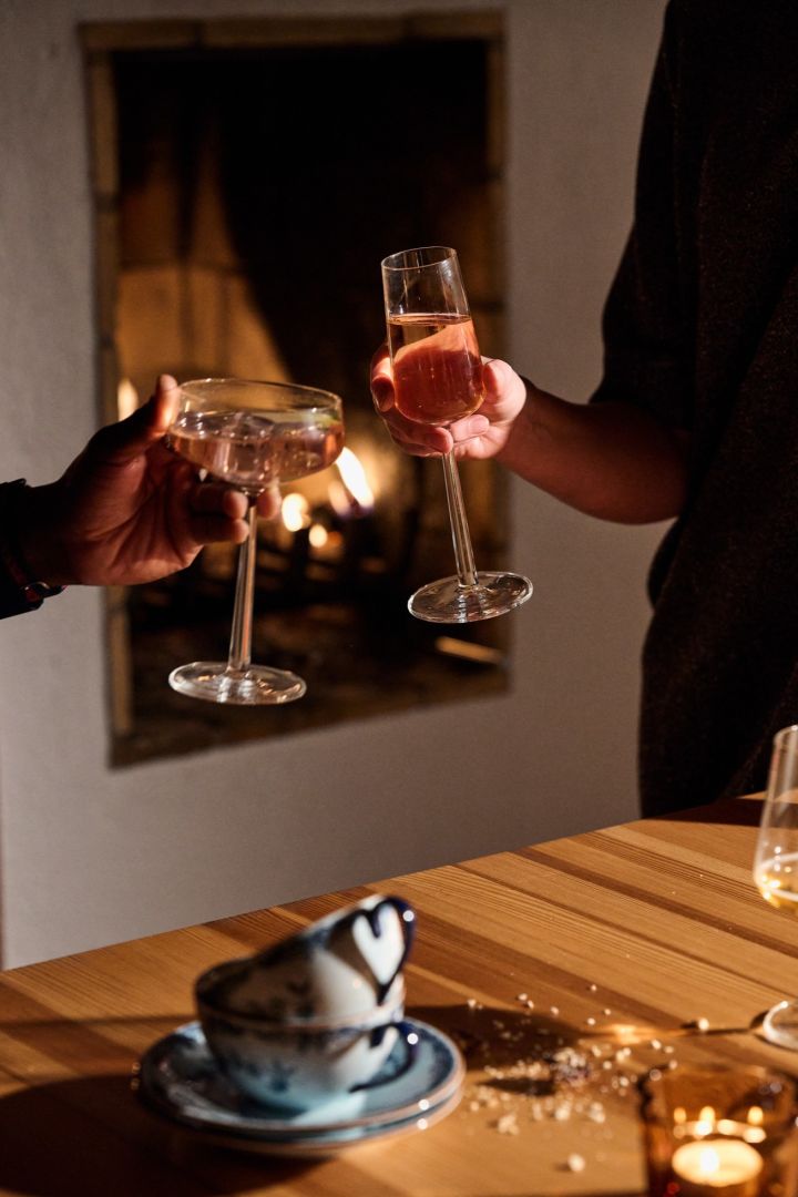 Des mains s'amusent avec deux verres Iittala Essence devant un feu lors d'une célébration nordique de Noël. 