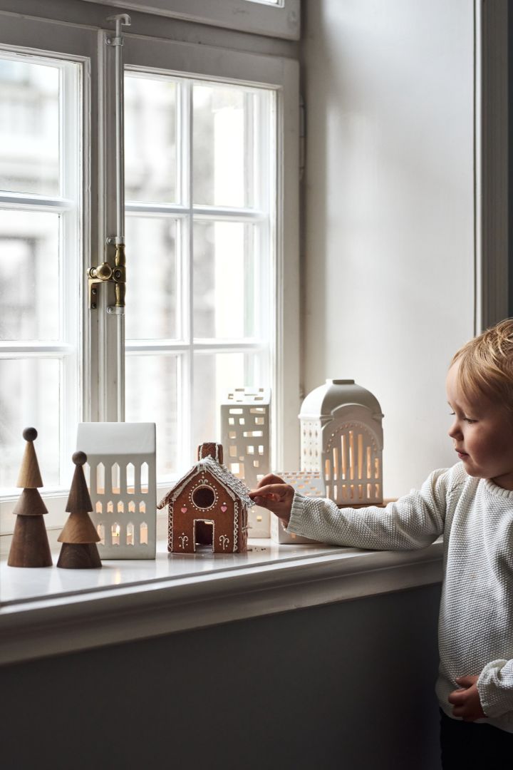 Décorez avec des décorations de Noël scandinaves traditionnelles comme les bougeoirs Urbania de Kähler. Vous en voyez ici une collection sur le rebord d'une fenêtre avec un jeune garçon. 