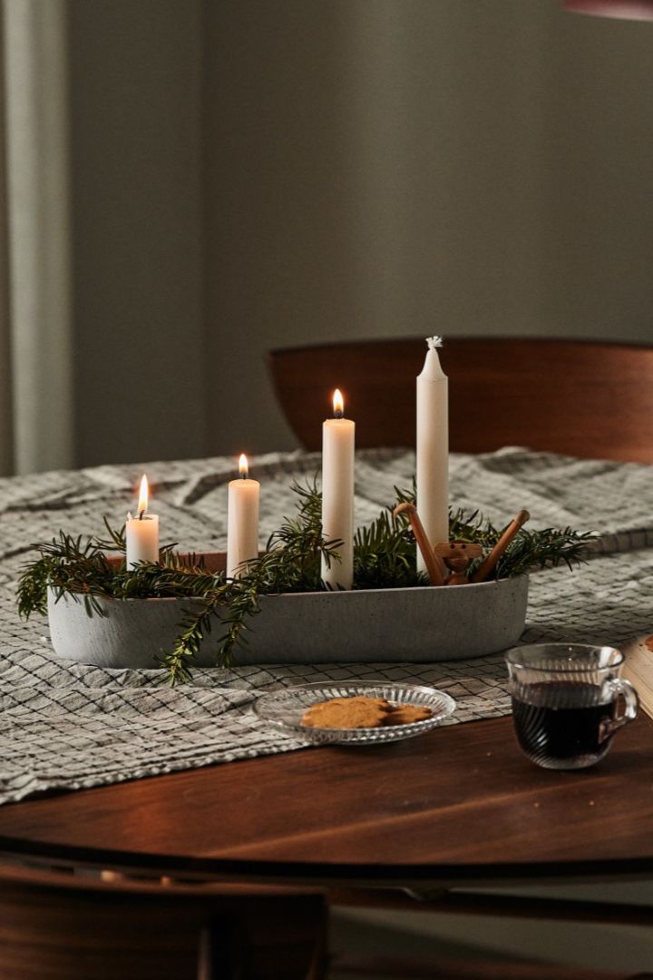 Vous voyez ici un bougeoir de Noël scandinave traditionnel posé sur la table avec du pain d'épices et une tasse de vin chaud. 