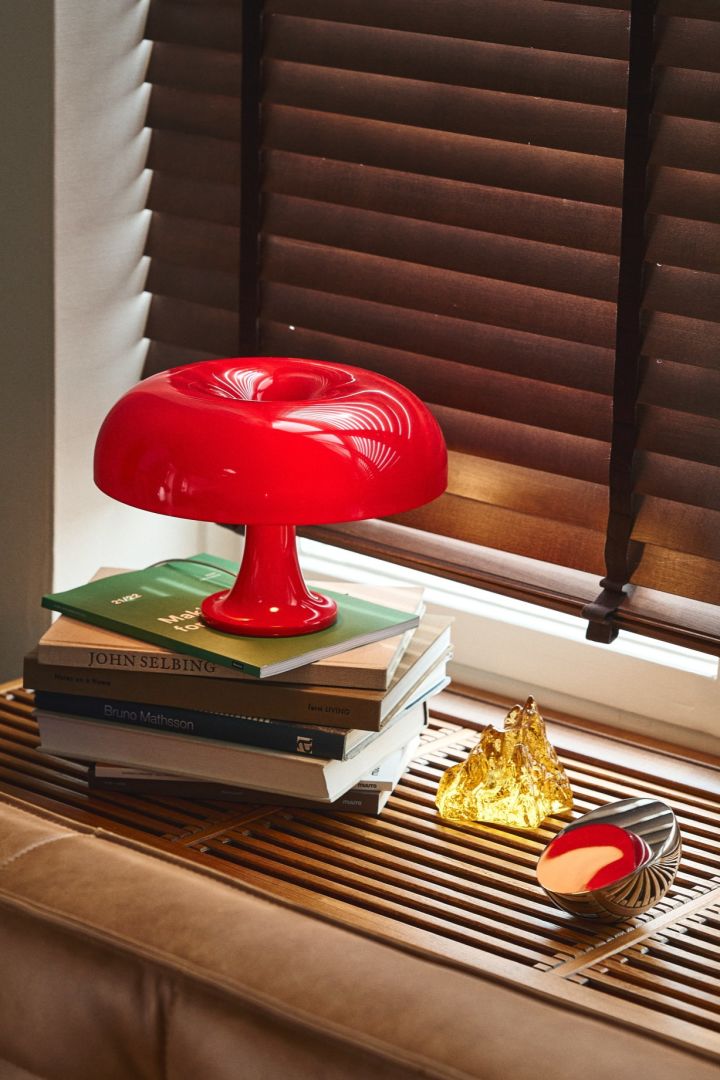 Mettez votre maison à jour avec des idées d'éclairage modernes comme le Nessino en rouge, favori d'Instagram, d'Artemide. Vu ici sur un rebord de fenêtre en bois avec un bougeoir jaune de Kosta Boda. 