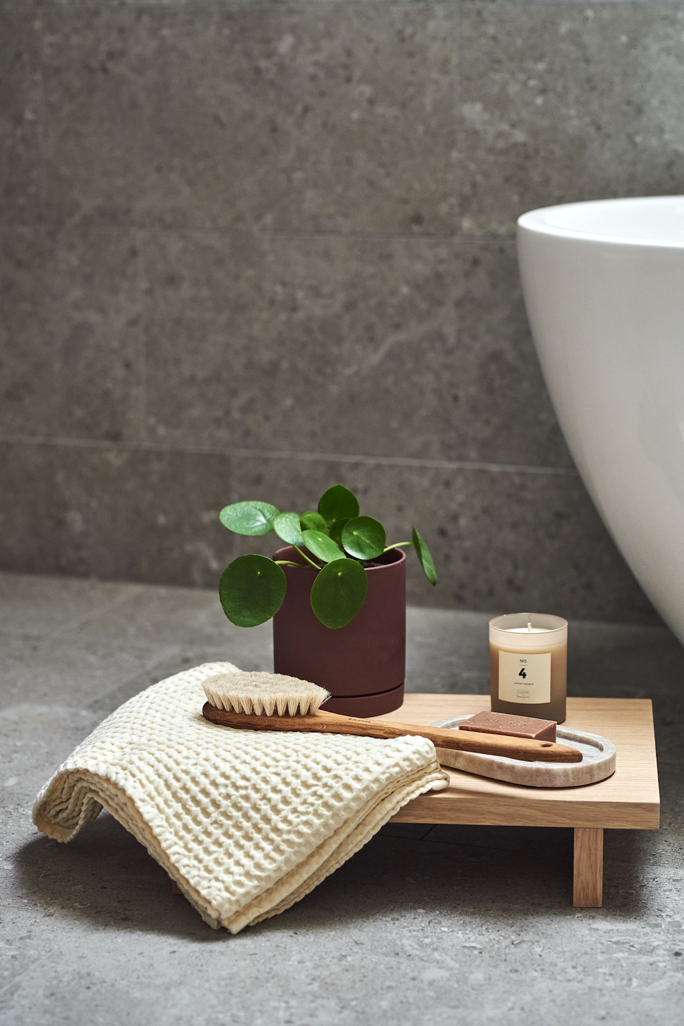 Brosse de bain d'Iris Hantverk, bougies parfumées de Bloomingville, savon et plateau en marbre de Meraki et serviette, pot et table d'appoint de Ferm Living - tout ce qu'il faut pour créer un spa relaxant à la maison pendant la Saint-Valentin.