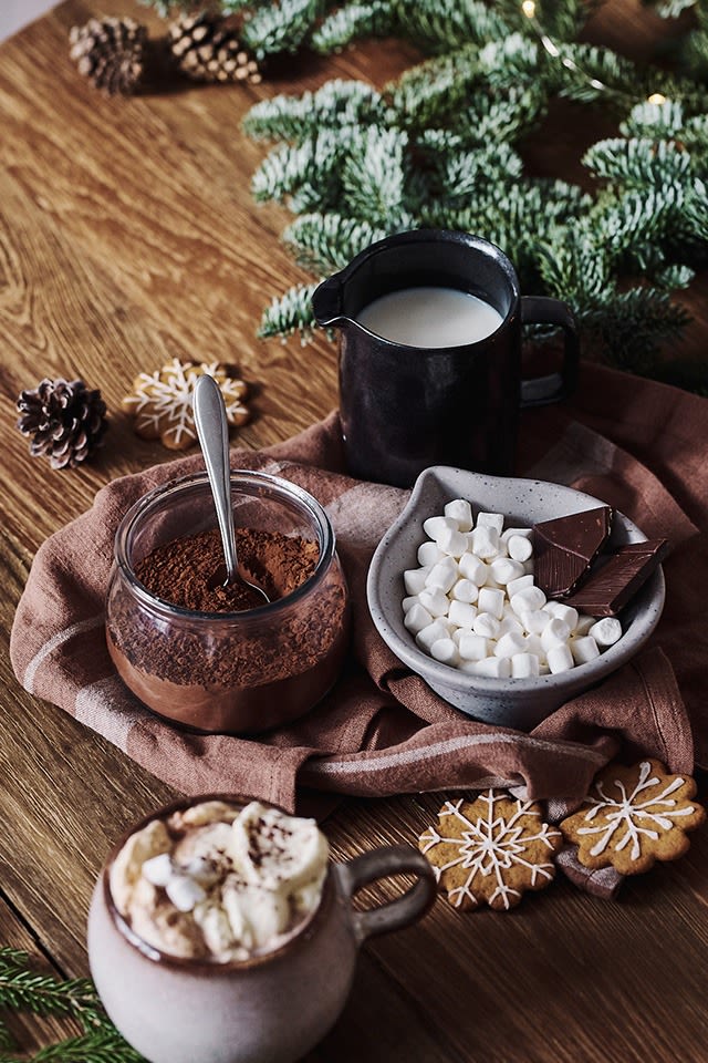 Les ingrédients pour un chocolat chaud fait maison, comme le cacao, le lait et les mini-guimauves, sont disponibles dans un petit bol.