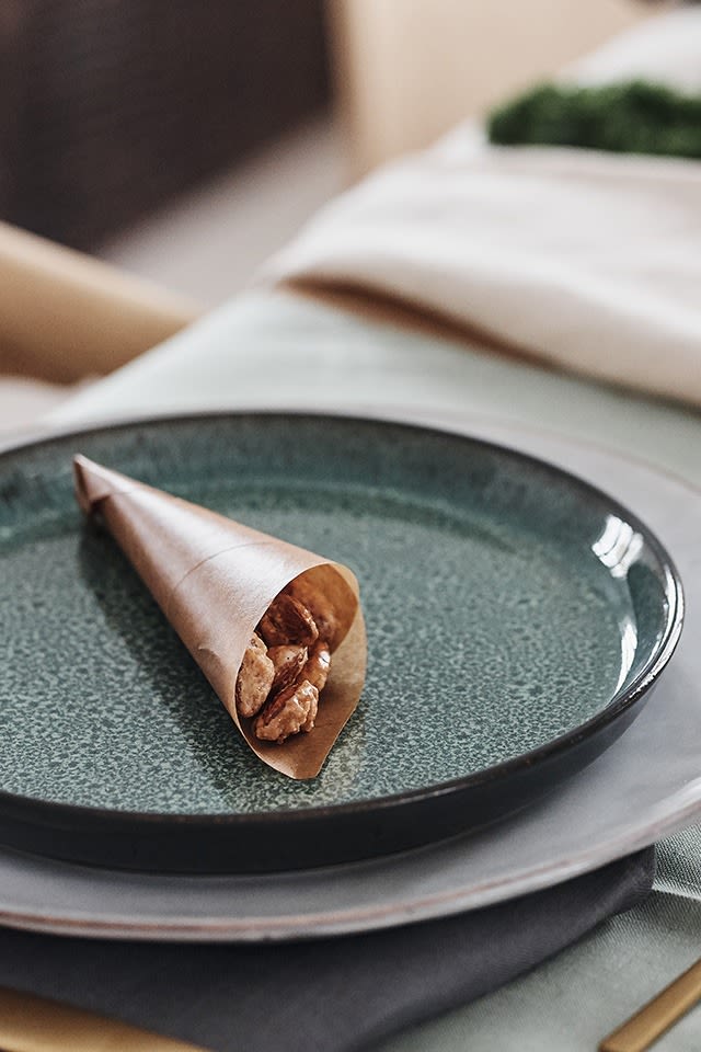 Les amandes confites dans des cônes en papier ciré sont placées sur l'assiette de la table de Noël en guise de bienvenue aux invités.