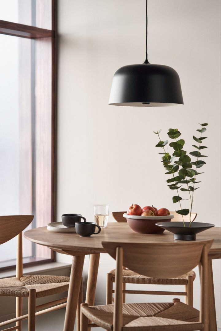 Rafraîchissez votre intérieur avec des plafonniers modernes. Ici, le plafonnier Halo de Scandi Living, de couleur noire, est suspendu au-dessus d'une table à manger ronde.  