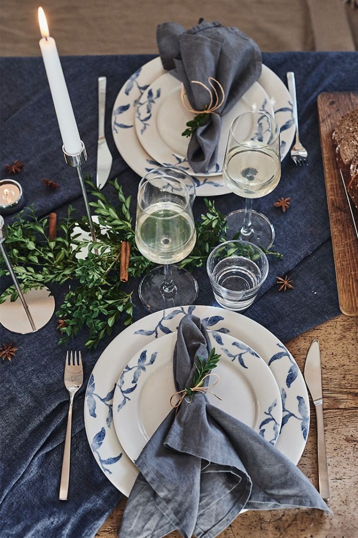 Table de Noël dressée de manière romantique avec de la porcelaine bleue et blanche Havspil de Scandi Living et des couverts Fuga de Gense. 