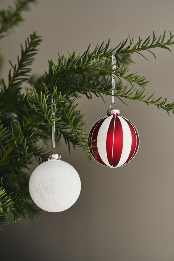 Voici des idées ludiques et colorées pour décorer le sapin de Noël : une boule rayée rouge et blanche de Scandi Living et une boule blanche pailletée, également de Scandi Living. 