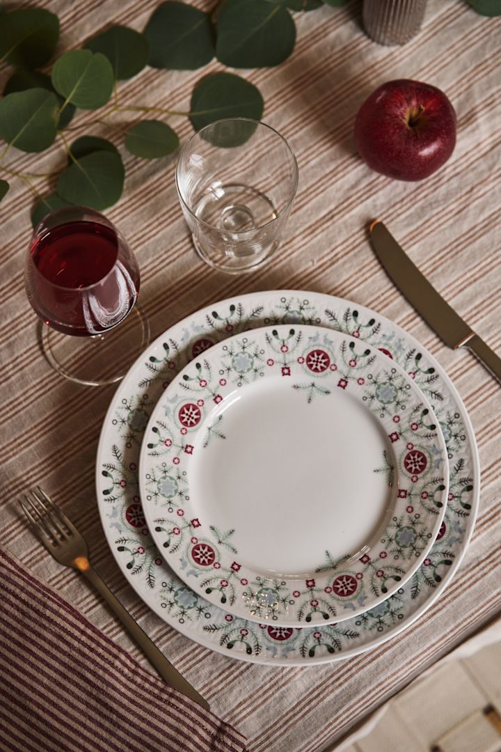 Rétroprojection d'un ensemble d'assiettes de Noël dans le cadre d'une idée simple de décoration de table de Noël. Avec une nappe rayée et des décorations de table simples et naturelles. 