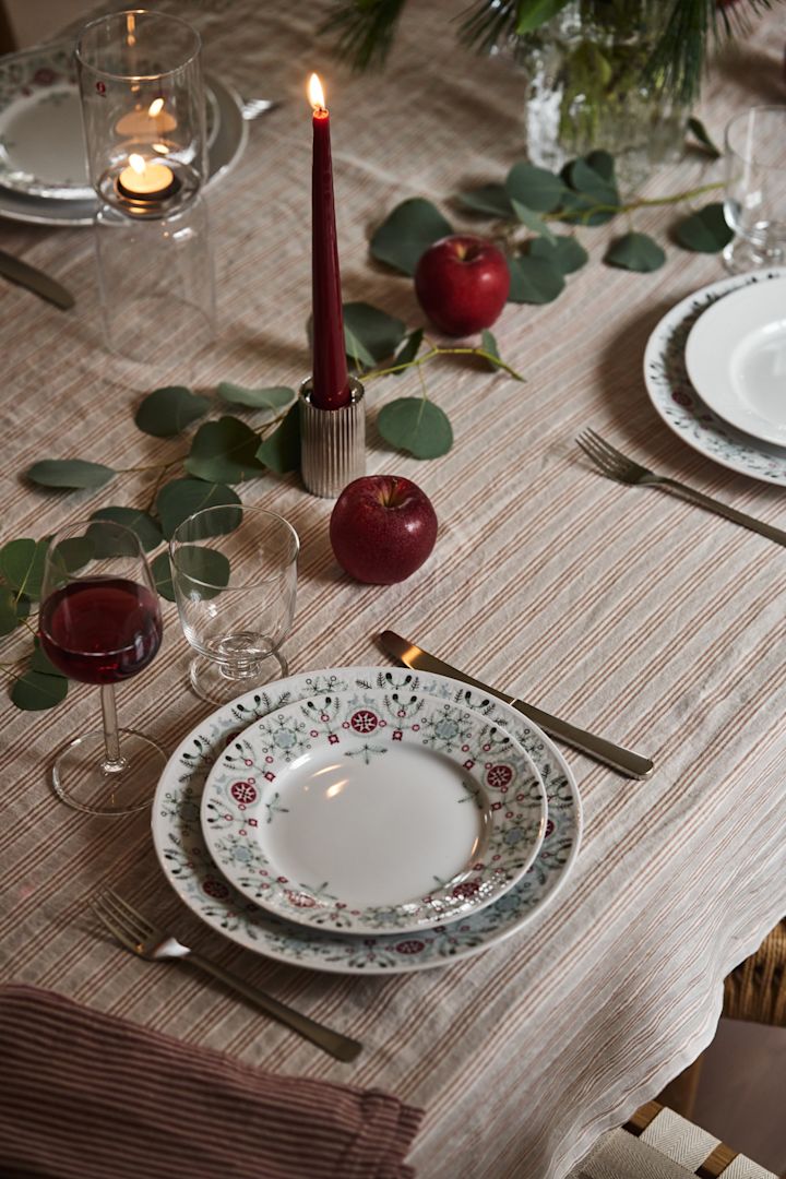 Une idée simple de table de Noël avec Swedish Grace Winter, des bougies rouges et de la verdure. 