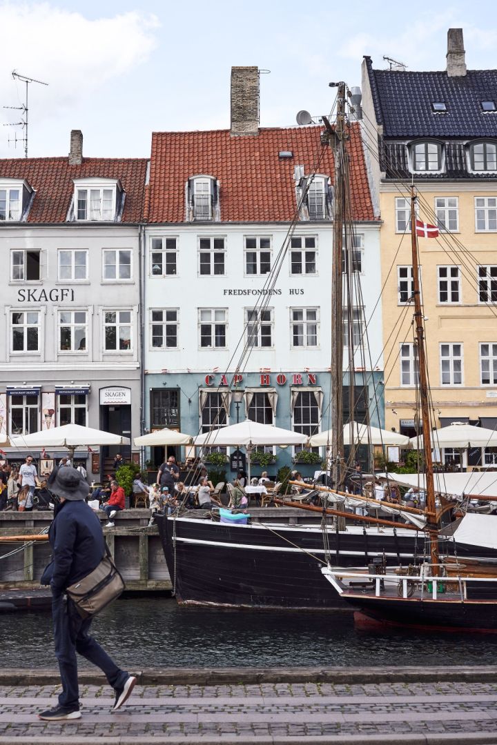 Le port de Nyhavn est une visite incontournable de Copenhague. Ici, vous voyez quelqu'un qui passe devant les bâtiments colorés du port. 