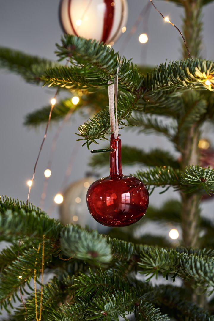 Décorez le sapin de Noël avec des décorations de sapin de Noël pour 2021 dans 4 styles différents selon les tendances Nest - Nurture, Share, Boost et Cultivate. Ici, vous voyez la pomme en verre Iittala en rouge.