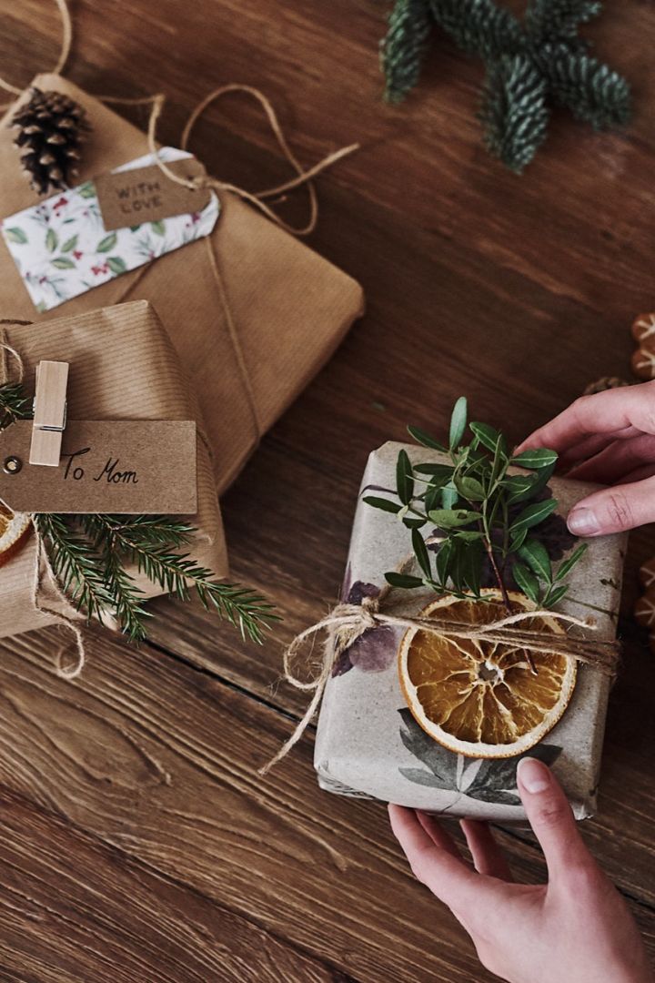 Cadeaux de Noël emballés dans du papier peint et décorés de tranches d'orange séchée et de branches de sapin.