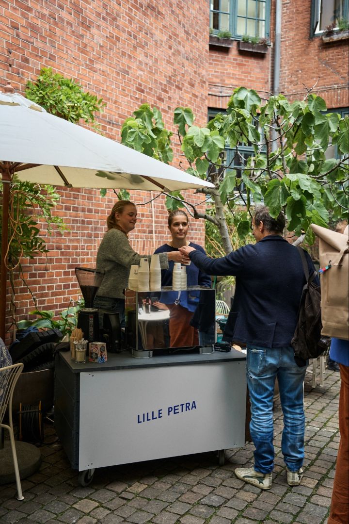 Arrêtez-vous au café Lille Petra lors de votre visite de Copenhague pour les amateurs de design. Ici, le personnel distribue du café dans la cour. 