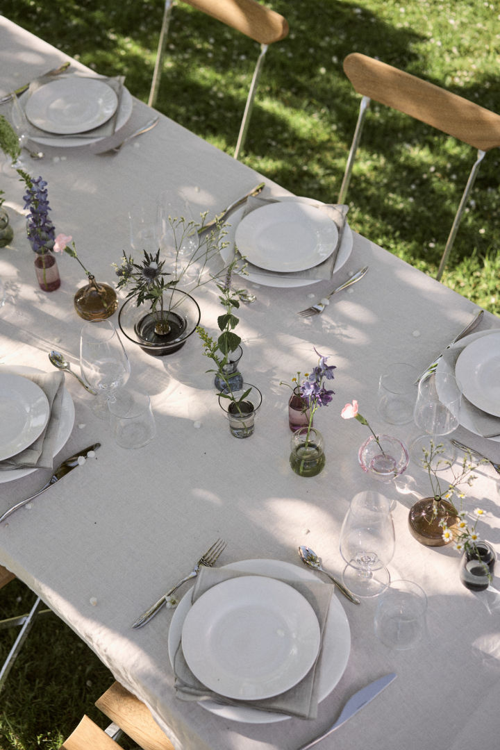 Une table dressée en blanc avec un mini vase midsummer de Orrefors comme pièce centrale.