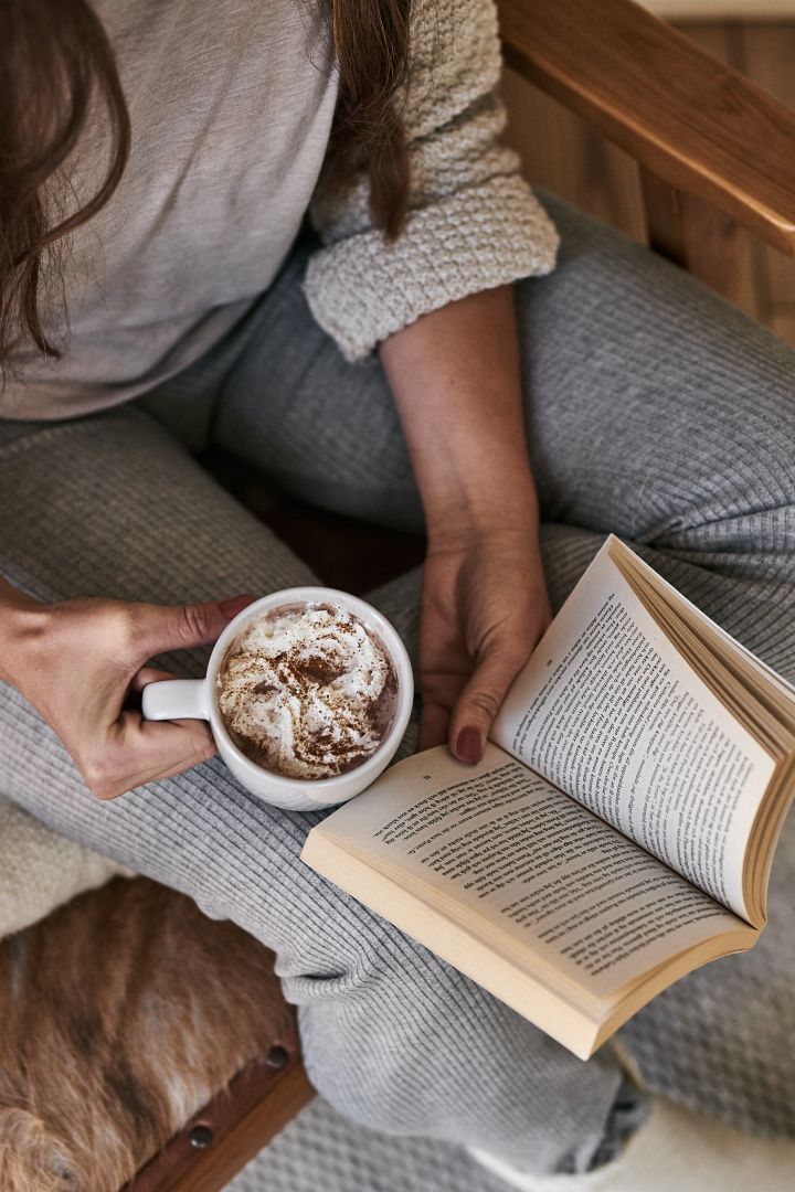 L'art de vivre scandinave à essayer cet hiver - lire un livre au coin du feu avec le mug Fossil de Scandi Living. 