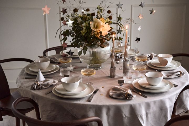 Des idées pour votre fête de la Saint-Sylvestre : si vous préférez la sobriété, laissez la décoration de table en blanc et ajoutez quelques touches isolées sous la forme d'un vase ou de ballons !