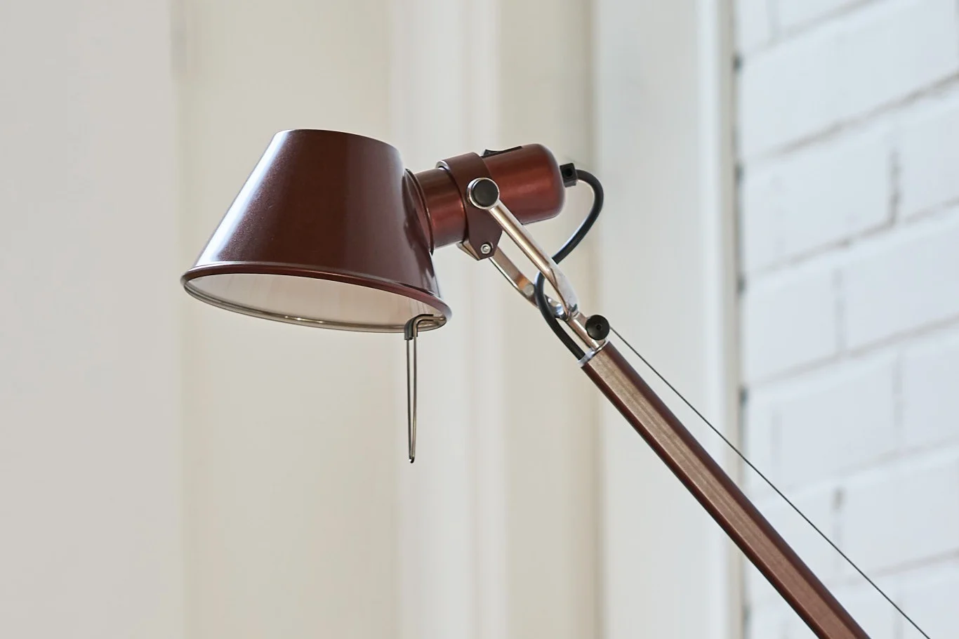 Gros plan d'une lampe de bureau marron réglable avec un abat-jour conique et des accents chromés.