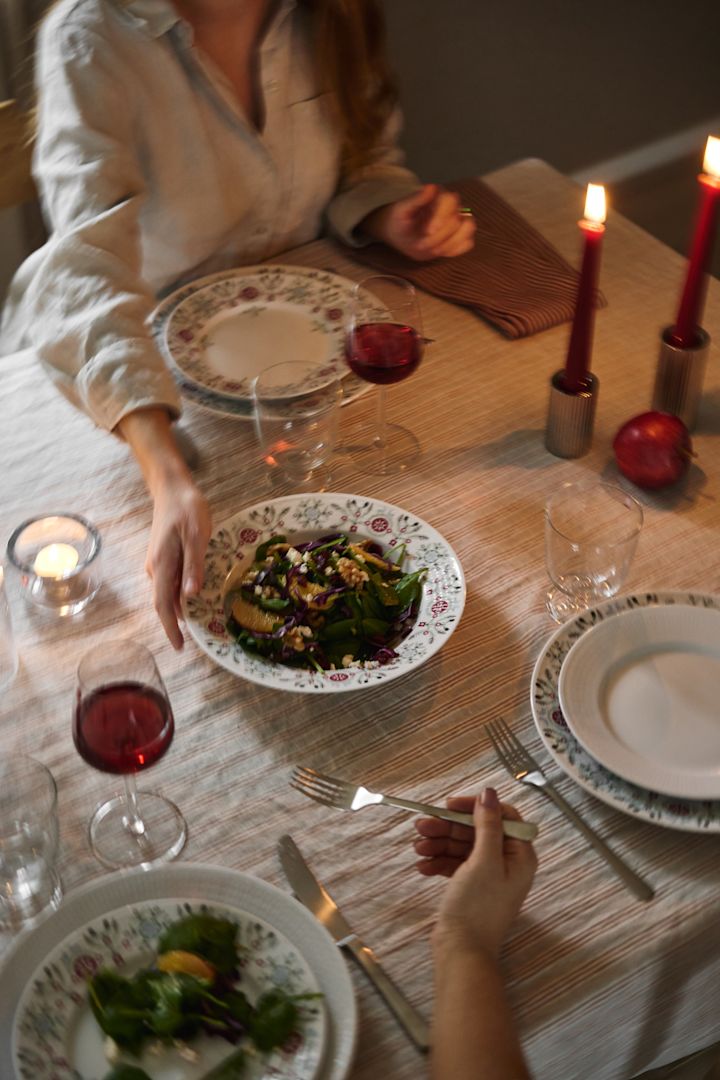 Une main fait passer une salade d'hiver sur la table dans le cadre d'une idée de table de Noël scandinave. 