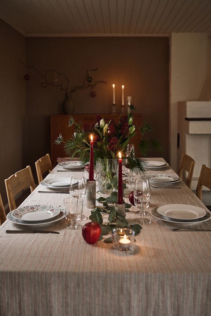 Une idée de table de Noël simple et atmosphérique avec des bougies rouges et de la vaisselle de Noël imprimée. 