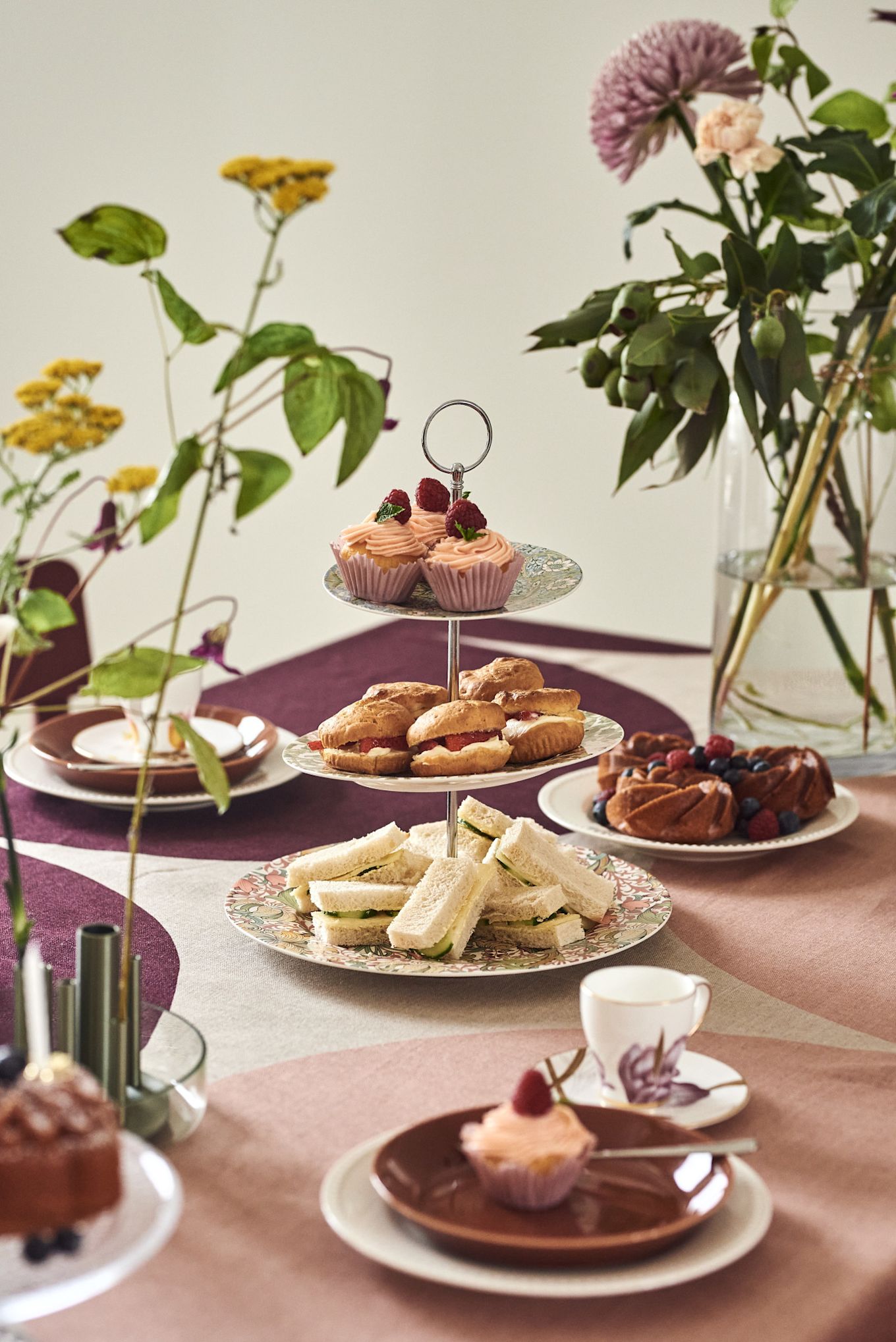 Une main tient une théière au-dessus d'une table préparée pour un goûter. 