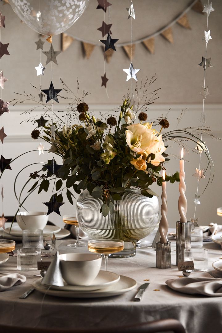 Idées pour votre fête de la Saint-Sylvestre : placez un grand vase avec un bouquet de fleurs à l'intérieur pour attirer l'attention au milieu de la table.